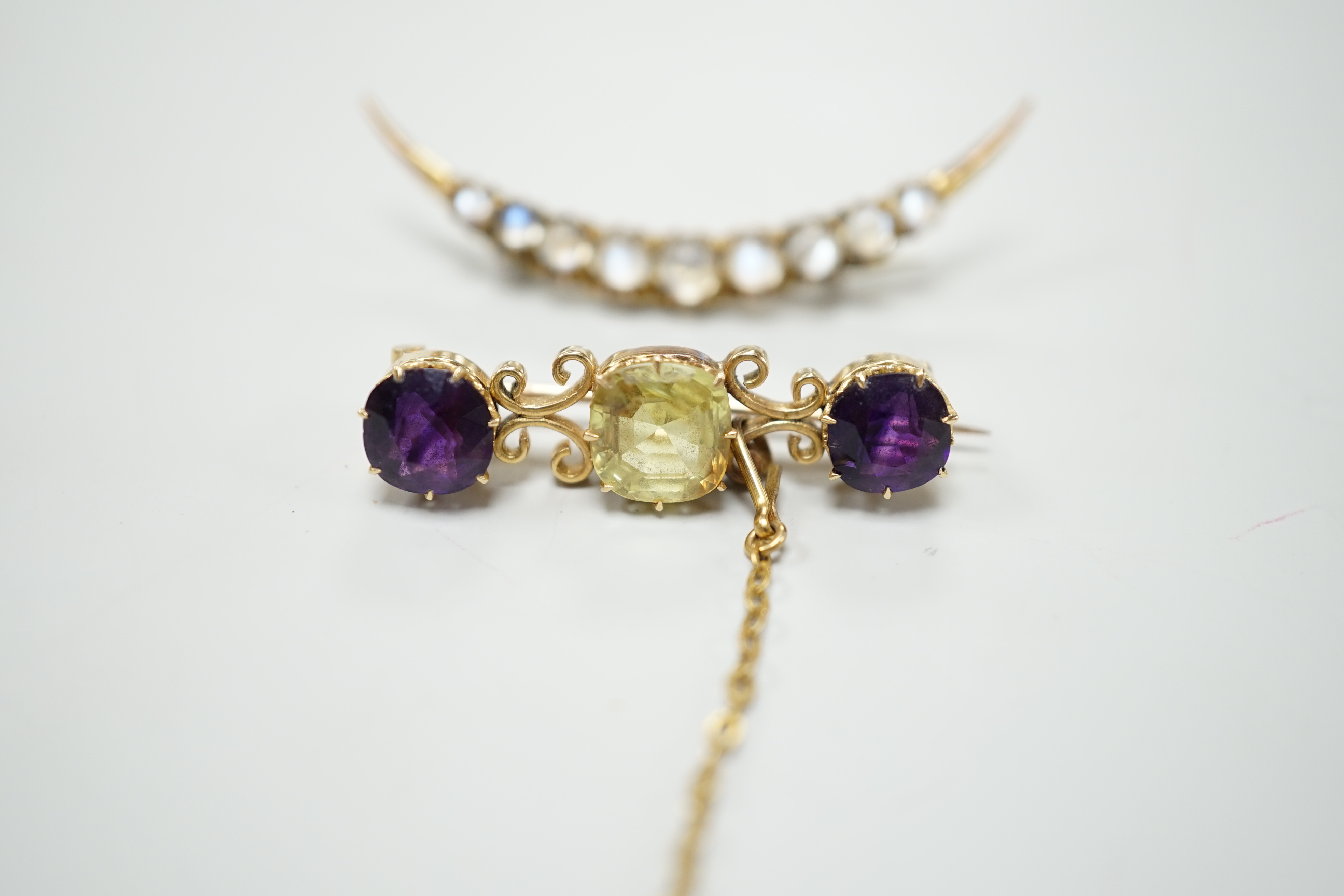 A gold and moonstone crescent shaped brooch, 4.7cm, gross 2.7 grams and an amethyst and gem set scrollwork bar brooch, 3.25 grams